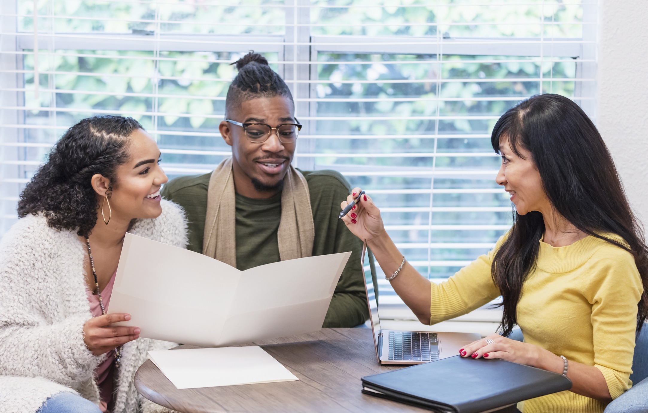 Young couple with advisor, signing paperwork